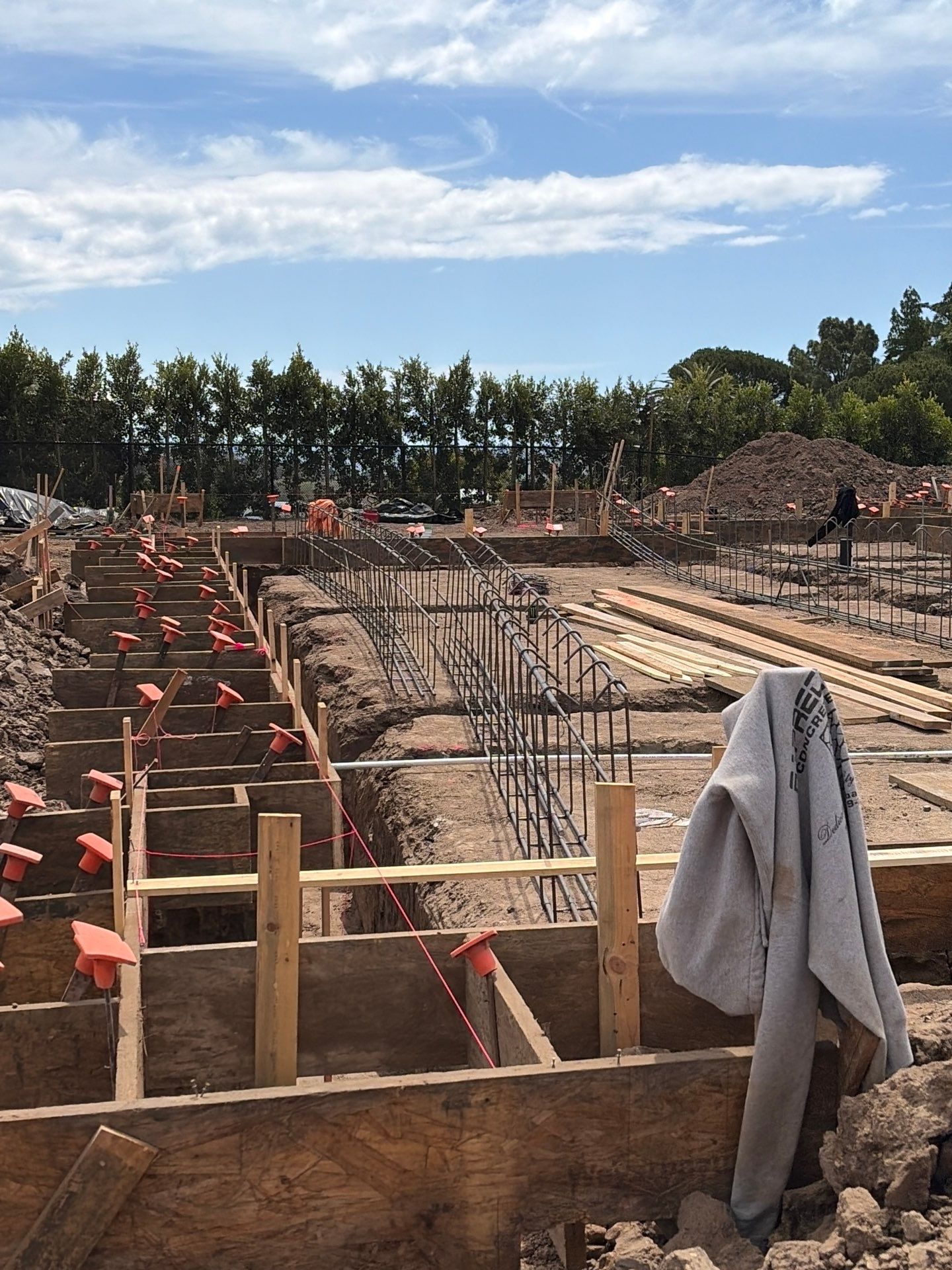 Rebar cages set in formed grade beam trenches, riding on chairs that hold the concrete cover