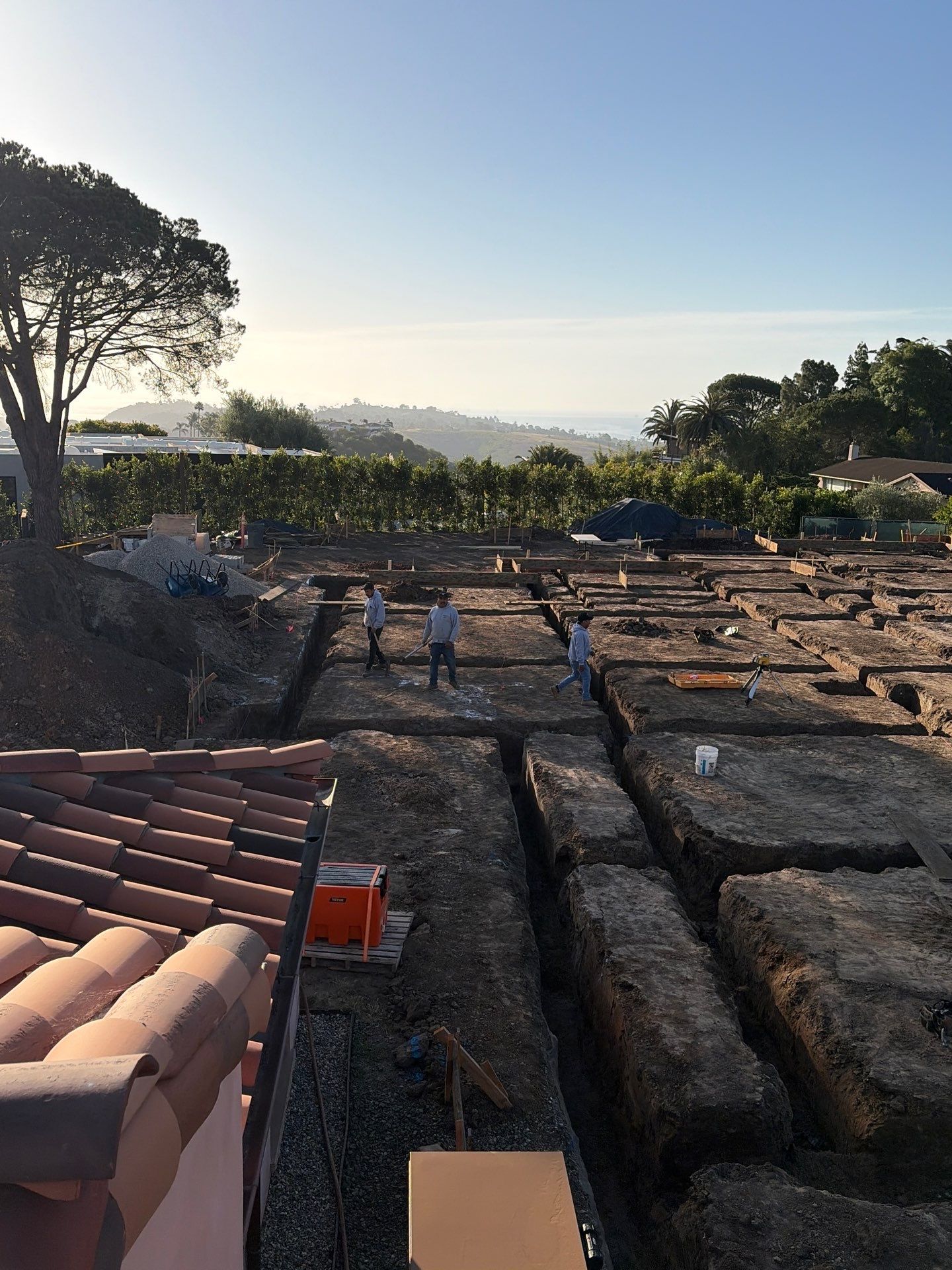 Foundation pad excavated to the footing and grade beam lines with the layout set across the site