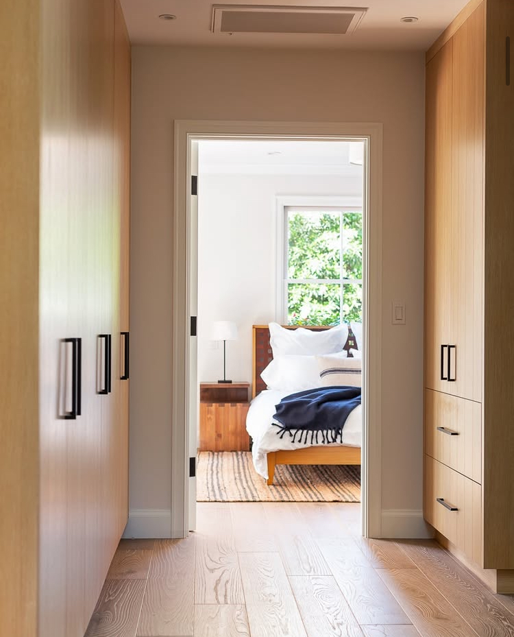 Oak-lined hallway looking into primary bedroom