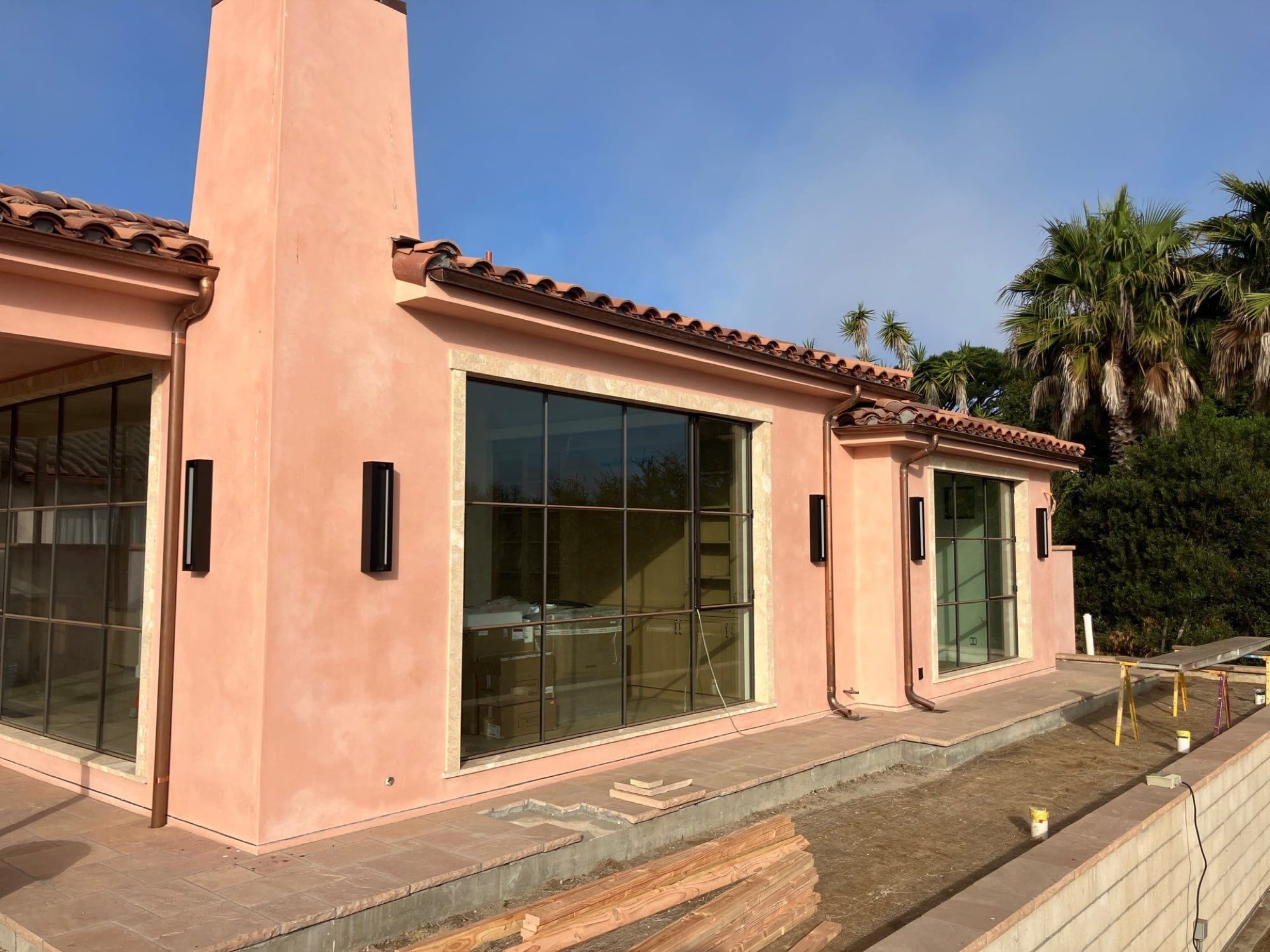 Spanish Modern ADU exterior with hand-troweled plaster, clay tile roof, steel-framed windows, and stone chimney
