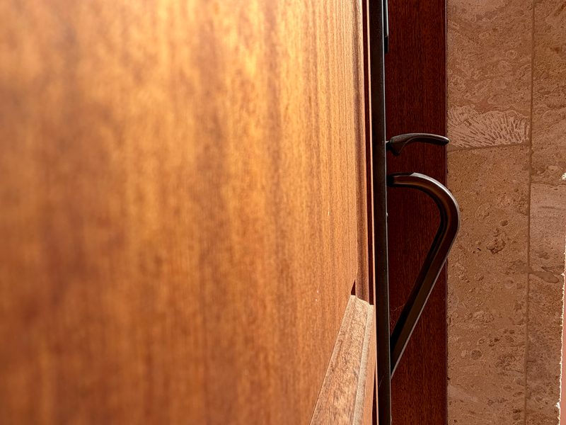 Mahogany entry door with wrought iron handle and stone surround