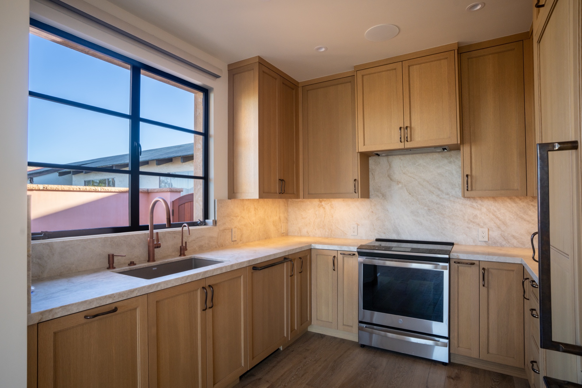 Kitchen with oak cabinetry, marble counters, and copper fixtures