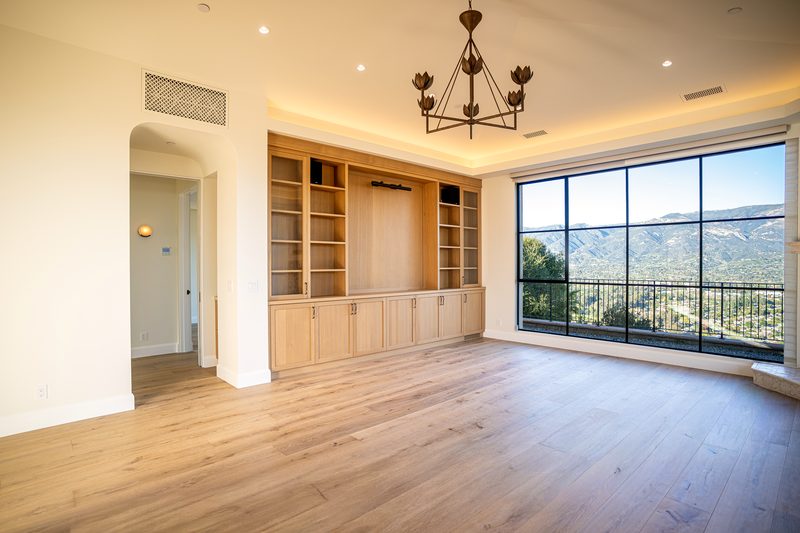 Open living room with oak built-in cabinetry, iron chandelier, cove lighting, and panoramic mountain views