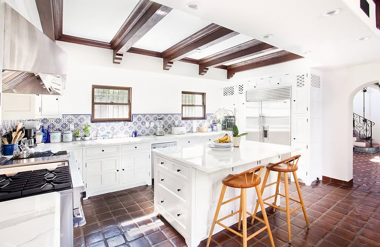 Spanish Revival kitchen with blue tile backsplash, brown tile floors, and beamed ceilings